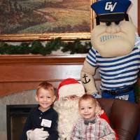 Two boys sitting with Santa & Louie at the event.